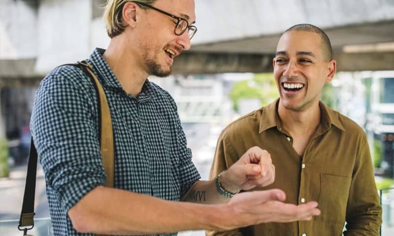Two men smiling and discussing outdoors, representing health and wellness.